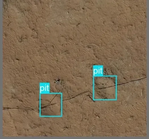 Drone view of bare terrain with two planting pits detected and boxed